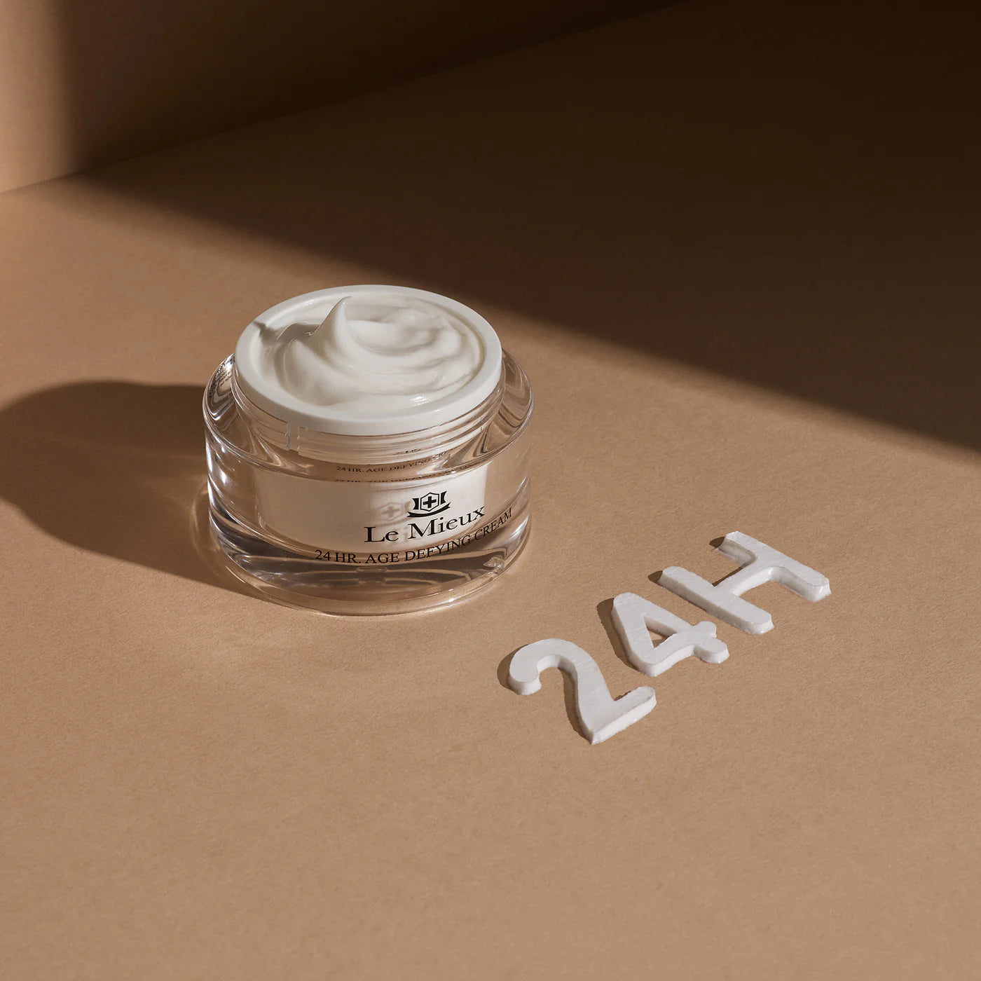 Le Mieux 24 Hr. Age Defying Cream jar styled on neutral background representing 24-hour hydration and firmness.