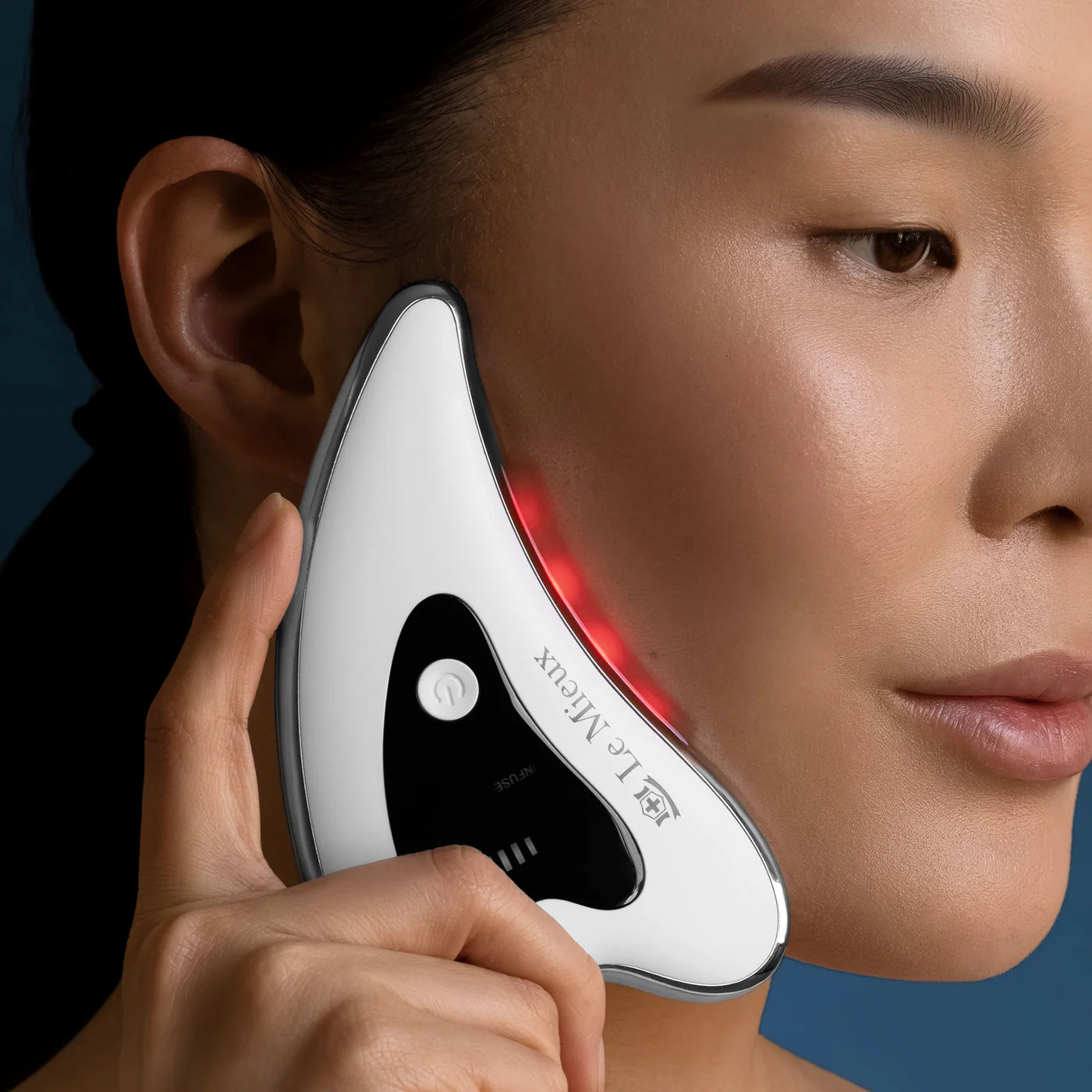Model using Le Mieux Gua Sha ThermaLift on cheek to lift, firm, and enhance facial contour with microvibrations and heat.