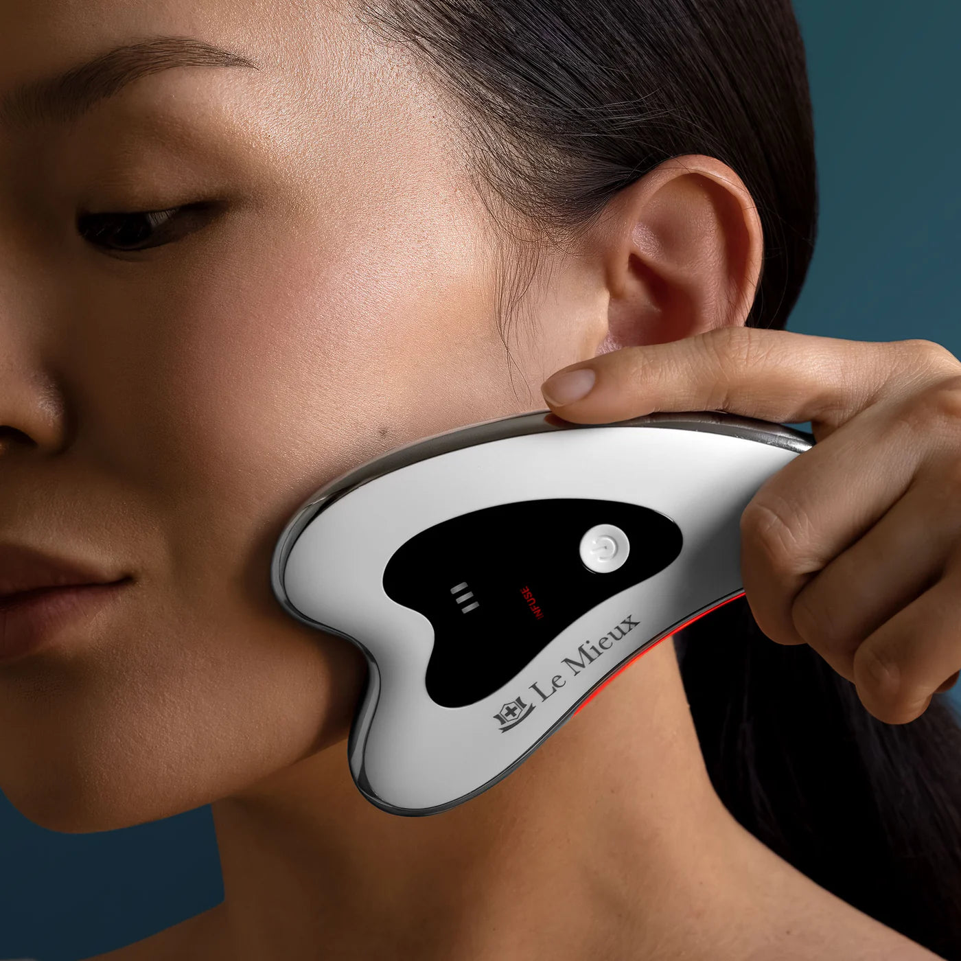 Model gliding Le Mieux Gua Sha ThermaLift along jawline and neck to reduce puffiness and improve microcirculation.